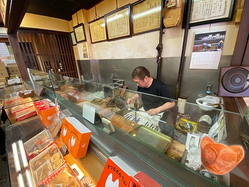 総本家　いなりやで煎餅を焼く店主